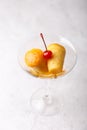 Neapolitan Rum baba or baba au rum in a martini glass with a cocktail cherry on a gray background. Small yeast cakes.