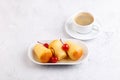 Neapolitan Rum baba on a white plate with a cocktail cherry and a cup of coffee. Small yeast cakes soaked in rum syrup