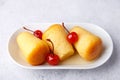 Neapolitan Rum baba on a white plate with a cocktail cherry and a cup of coffee. Small yeast cakes soaked in rum syrup.