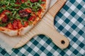 Neapolitan spicy pizza with ham, cheese, arugula, basil, tomatoes, pepperoni pepper sprayed with cheese on a wooden board on a Royalty Free Stock Photo