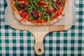 Neapolitan spicy pizza with ham, cheese, arugula, basil, tomatoes, pepperoni pepper sprayed with cheese on a wooden board on a Royalty Free Stock Photo