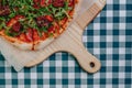 Neapolitan spicy pizza with ham, cheese, arugula, basil, tomatoes, pepperoni pepper sprayed with cheese on a wooden board on a Royalty Free Stock Photo