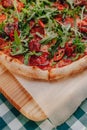 Neapolitan spicy pizza with ham, cheese, arugula, basil, tomatoes, pepperoni pepper sprayed with cheese on a wooden board on a Royalty Free Stock Photo