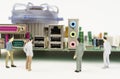 Near the motherboard of the computer are miniature figurines of people. Figures out of focus.
