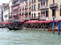 Near the old houses of the pier with gondolas on the water and restaurants in Venice, Italy. Historical tourist monument Royalty Free Stock Photo