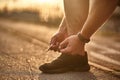 A man in a light athletic uniform ties a lace on a shoe for running. Sport concept