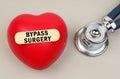 Near the stethoscope lies a heart on which a sticker is pasted with the inscription - Bypass Surgery