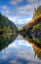 Nearly perfect fall reflections with blue sky and fluffy white clouds while rafting down the Rogue River in Oregon Royalty Free Stock Photo