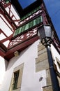 Neat half-timbered facade with red beams and green window frames and a street lamp 2