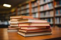 Neat stack of books on table, library bookshelf blurred behind Royalty Free Stock Photo