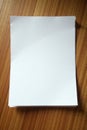 Neat stack of crisp white printer paper on wood, orderly, unwrinkled, sharp