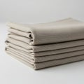 A neat stack of folded beige fabric napkins rests on a smooth white surface. The Royalty Free Stock Photo