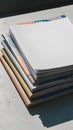 Neat stack of papers or magazines with blank top paper, colorful designs visible Royalty Free Stock Photo