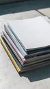 Neat stack of papers or magazines with blank top paper, colorful designs visible Royalty Free Stock Photo