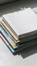 Neat stack of papers or magazines with blank top paper, colorful designs visible Royalty Free Stock Photo