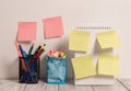 Neat Workplace with 6 Empty Colored Stick Pad Notes Put on Both White Wall and Open Spiral Notebook with 2 Full Pencil
