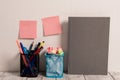 Neat Workplace with Empty Colored Stick Pad Notes Put on White Wall and Two Full Pencil Pots and Grey Hardcover Notebook