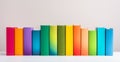 Neatly arranged books in a vibrant rainbow spectrum on a clean white shelf