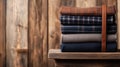Stack of folded xadrez fabric shirts in earthy tones with leather suspender on rustic wooden shelf Royalty Free Stock Photo