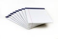 A neatly arranged stack of white, ruled notepads with blue binding