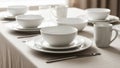 A neatly arranged table set with white ceramic dinnerware, including bowls, plates, and mugs. Royalty Free Stock Photo