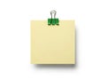 A neatly attached yellow sticky note secured with a green binder clip on a plain background Royalty Free Stock Photo
