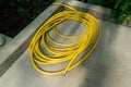A neatly coiled, bright yellow garden hose rests on a concrete surface Royalty Free Stock Photo