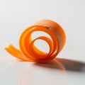 A neatly curled orange carrot peel rests on a smooth, white surface Royalty Free Stock Photo