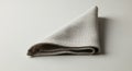 A neatly folded beige cloth napkin rests on a smooth, light-colored surface. The napkin has a Royalty Free Stock Photo