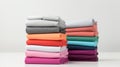 neatly folded colorful t-shirts in a gradient stack light to dark tones against a white background