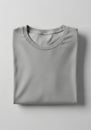 A neatly folded, light gray T-shirt with a round neckline is resting on a smooth, white Royalty Free Stock Photo