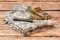 Neatly folded military camouflage clothes with gloves and torch.