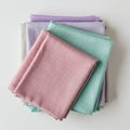 A neatly folded stack of multicolored fabric cloths placed on a white surface. The Royalty Free Stock Photo