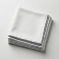 A neatly folded stack of white fabric napkins on a light surface. The napkins have a Royalty Free Stock Photo