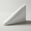A neatly folded white napkin stands on a neutral background in a triangular shape. Th Royalty Free Stock Photo