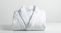 A neatly folded, white plush bathrobe is set against a plain, light-colored background. Royalty Free Stock Photo
