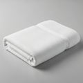 A neatly folded, white, terry cloth towel is positioned on a smooth, light gray surface. Royalty Free Stock Photo