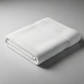 A neatly folded white towel lies on a smooth, light gray surface. The towel featu Royalty Free Stock Photo