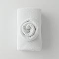 A neatly folded white towel on a light surface, featuring a decorative rose pattern. The Royalty Free Stock Photo