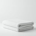 A neatly folded white towel placed on a flat surface against a plain white background. Royalty Free Stock Photo