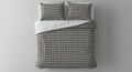 A neatly made bed features two pillows and a duvet cover with a stylish black and white houndstooth pattern, presented in a clean Royalty Free Stock Photo
