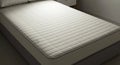 A neatly made bed features a white mattress with quilted horizontal stitching, Royalty Free Stock Photo