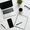 A neatly organized workspace features a silver laptop, a spiral-bound notebook
