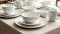 A neatly set dining table features white ceramic dinnerware including plates, bowls, and mugs Royalty Free Stock Photo