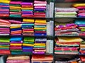 Neatly stacked colorful designer silk saris in racks in a textile shop. Incredible India