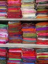 Neatly stacked colorful designer silk saris in racks in a textile shop. Incredible India