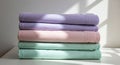 A neatly stacked pile of pastel-colored bed linens sits on a flat, white surface. The stack Royalty Free Stock Photo