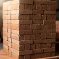 A neatly stacked pile of rectangular, reddish-brown bricks sits on a surface. The bricks display a Royalty Free Stock Photo