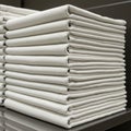 A neatly stacked pile of white cloth napkins is resting on a smooth, reflective surface. Royalty Free Stock Photo