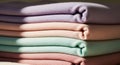 A neatly stacked set of folded, pastel-colored fabric or clothing items is displayed. Royalty Free Stock Photo